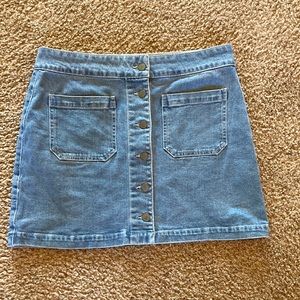 Short denim skirt with buttons and pockets on front.